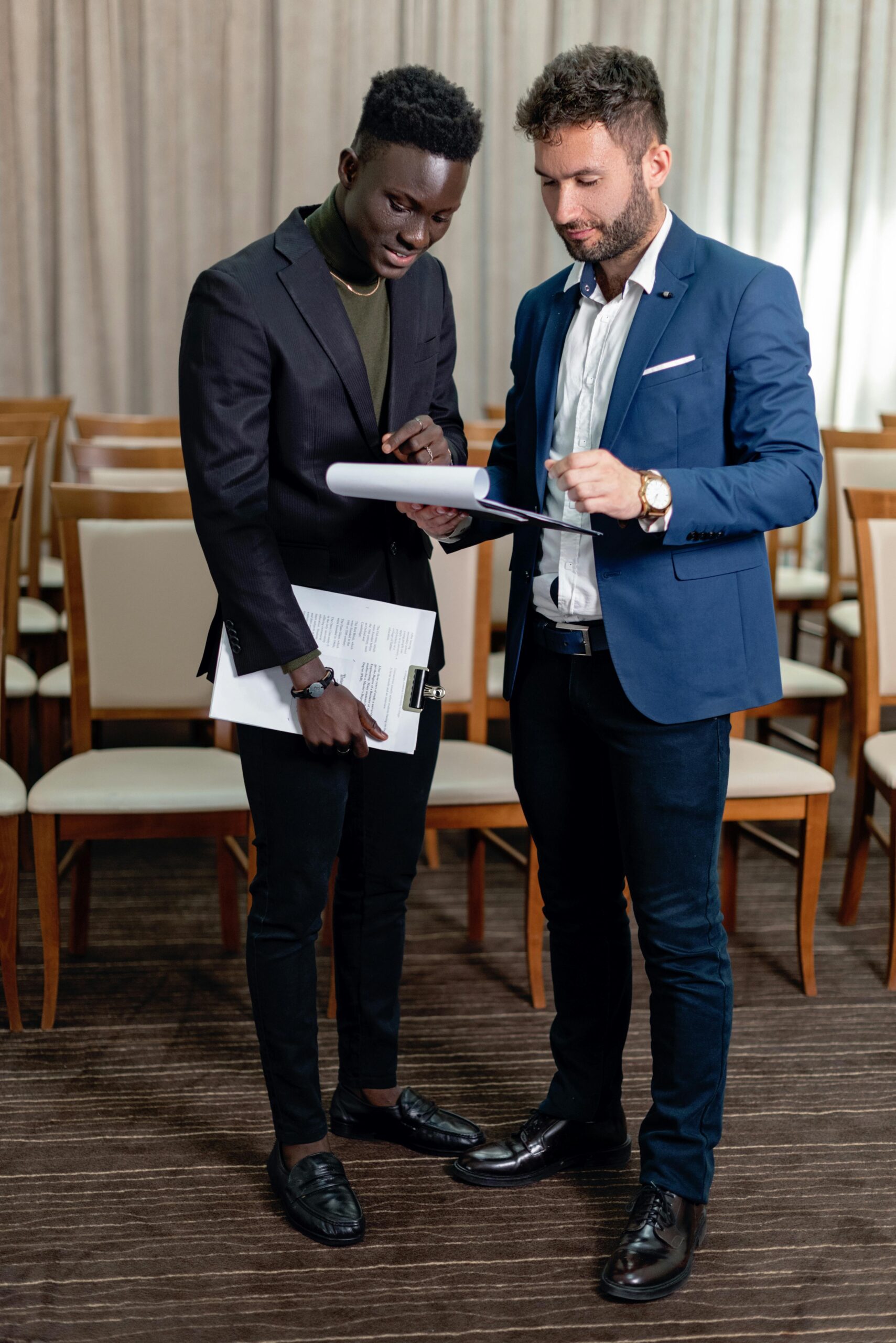 Two businessmen discussing documents in a formal meeting setting.